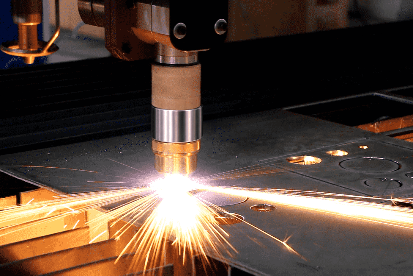 CNC plasma cutting torch slicing through a steel plate with bright sparks